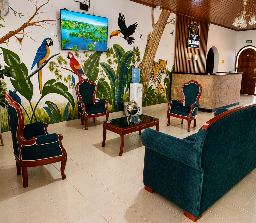 Sala de estar de El Jaguar Casa Hotel con sillones verdes, lámparas de araña y mural amazónico