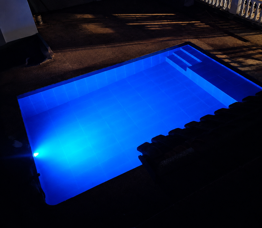 Piscina de El Jaguar Casa Hotel iluminada de azul durante la noche
