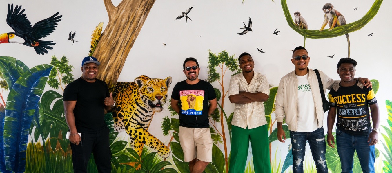 Grupo de huéspedes frente al mural con jaguar, tucanes y monos de la Amazonía en El Jaguar Casa Hotel