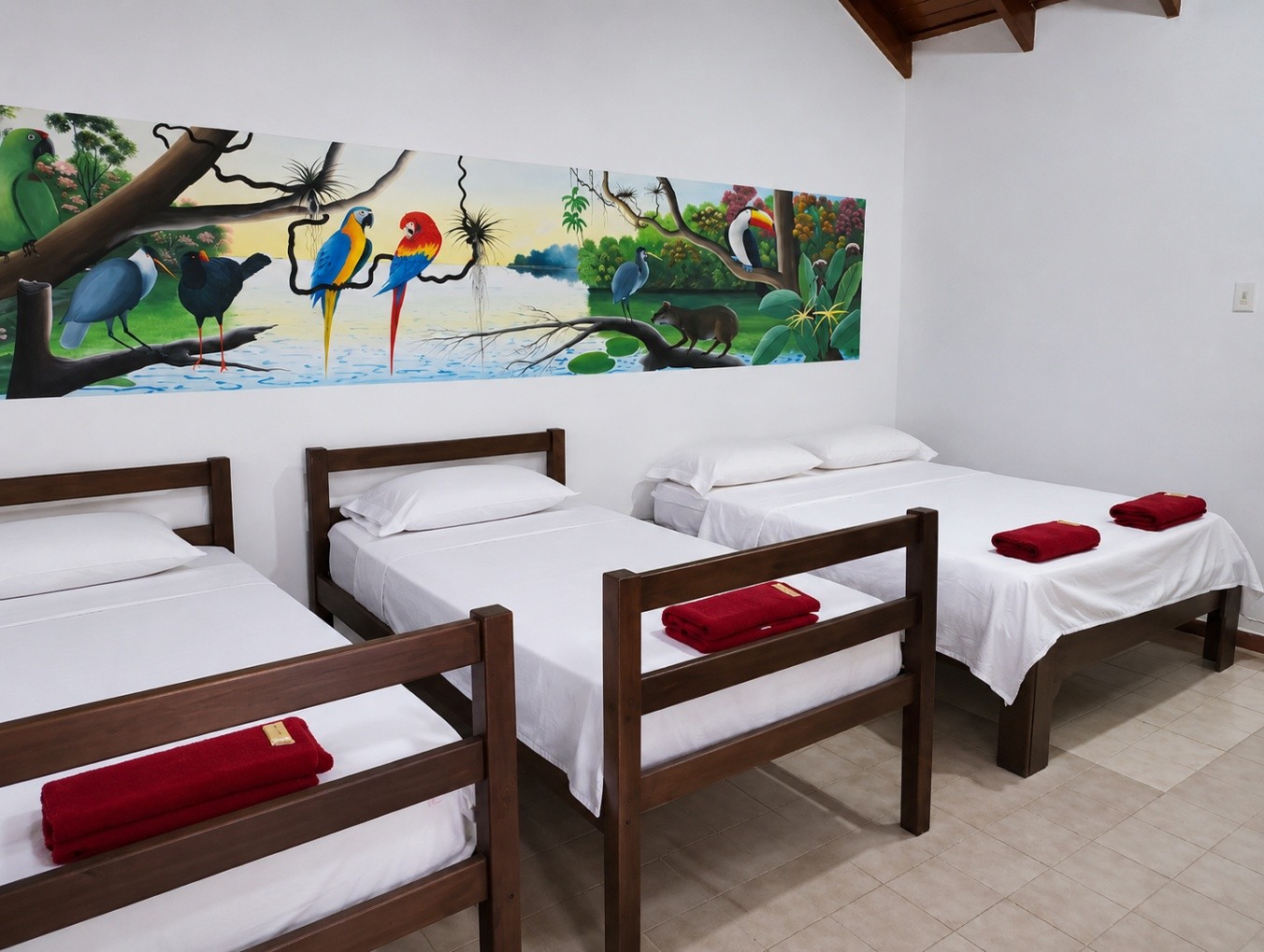 Suite Selva Triple en El Jaguar Casa Hotel con tres camas y mural de aves amazónicas